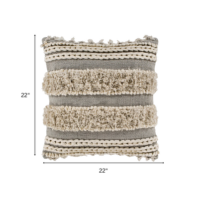 Beige and cream boho accent pillow with tassels and striped texture on a cozy neutral-toned sofa

