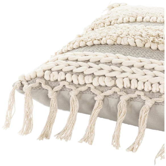 Beige and cream boho accent pillow with tassels and striped texture on a cozy neutral-toned sofa

