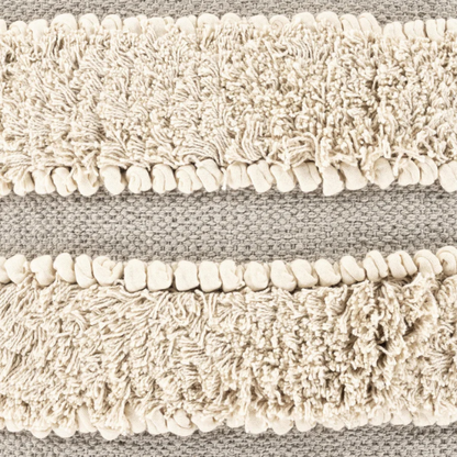 Beige and cream boho accent pillow with tassels and striped texture on a cozy neutral-toned sofa

