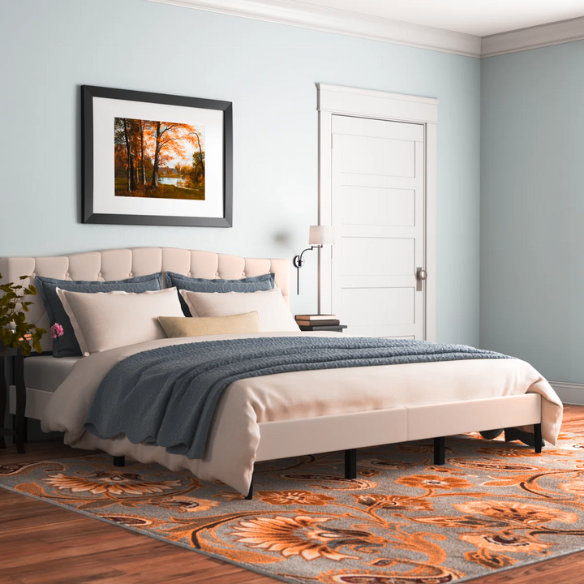 Beige king-size upholstered platform bed with camelback tufted headboard, foam padding, and low-profile wood frame with underbed clearance

