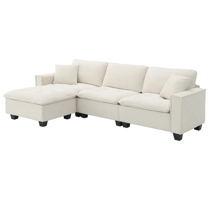Beige suede L-shaped sectional sofa with removable ottoman, tufted seat cushions, and two matching accent pillows