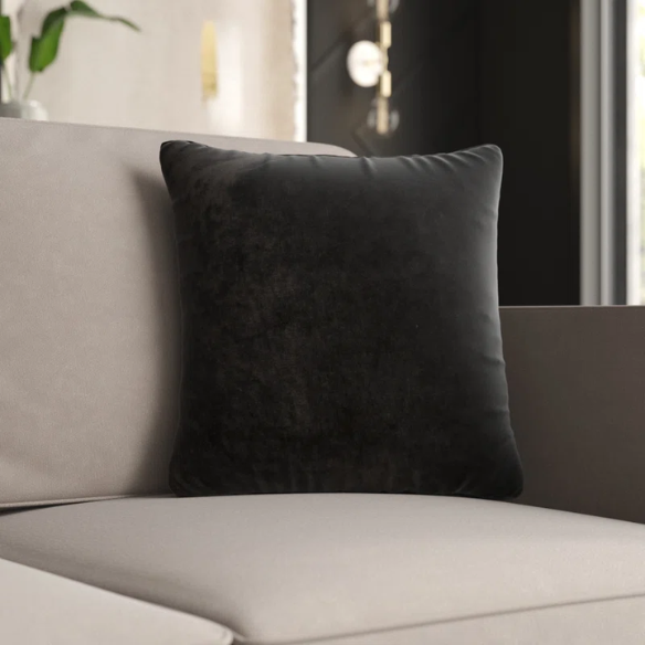 Black crushed velvet throw pillow, 16x16 square with soft texture and reversible design, styled on a modern sofa for elegant, cozy home decor.

