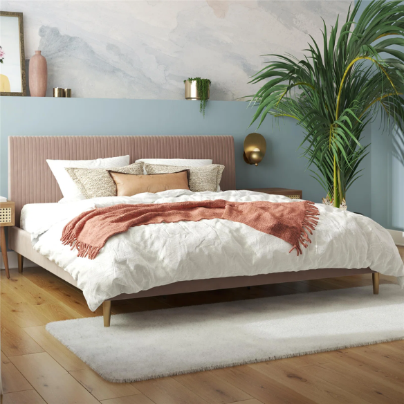 Blush pink velvet upholstered king-size platform bed with padded rectangular headboard, solid wood slats, and elegant low-profile frame.

