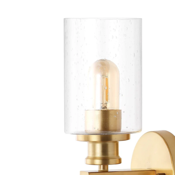 Rich brass wall sconce with dual clear seeded glass cylinder shades and Edison-style LED bulbs, perfect for upscale bathroom or hallway lighting

