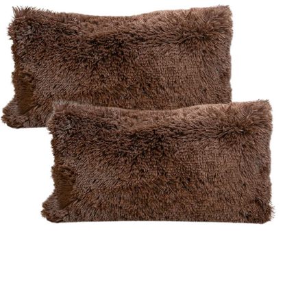 Set of two brown faux fur throw pillows with plush shaggy texture on a rustic wood-accented couch

