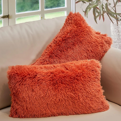 Set of two burnt orange faux fur throw pillows with shaggy texture on a modern sofa

