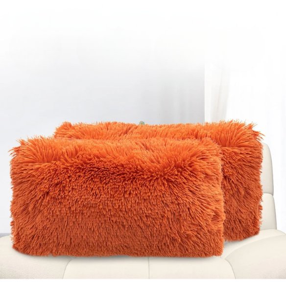 Set of two burnt orange faux fur throw pillows with shaggy texture on a modern sofa


