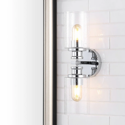 Polished chrome wall sconce with dual clear seeded glass cylinder shades and Edison-style LED bulbs, ideal for modern bathrooms or entryways

