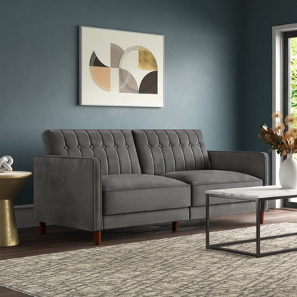 Dark grey velvet convertible sofa with vertical tufting, split-back design, square arms, and brown tapered legs, convertible into a twin-size sleeper.