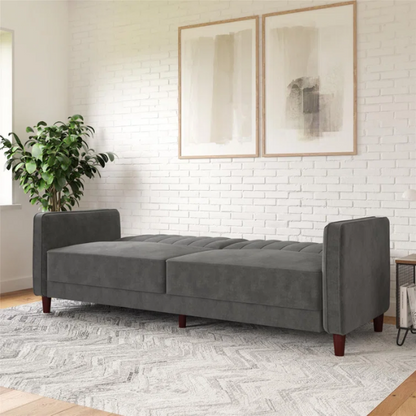 Dark grey velvet convertible sofa with vertical tufting, split-back design, square arms, and brown tapered legs, convertible into a twin-size sleeper.