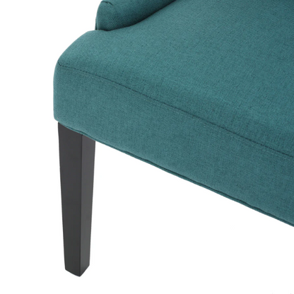 Set of four deep teal upholstered dining chairs with diamond tufted backs, armless design, sloped sides, and espresso brown wooden legs.

