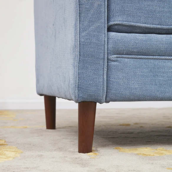 Dusty blue chenille upholstered sofa featuring curved track arms, tapered wooden legs, and foam-filled cushions in a mid-century modern design.