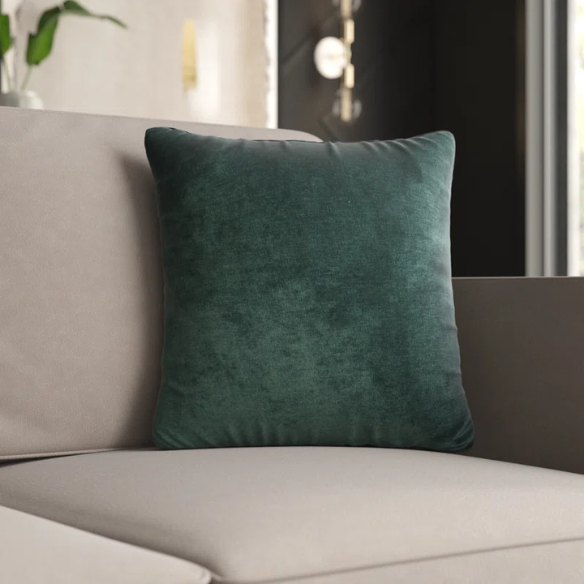 Emerald green crushed velvet throw pillow, 16x16 square design with soft texture and reversible fabric, styled on a modern sofa for vibrant, luxurious home decor.

