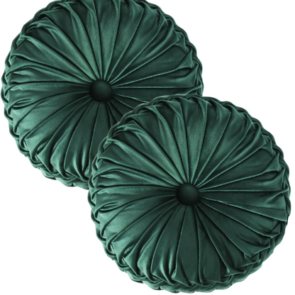 Emerald green velvet round throw pillows with hand-pleated detail and central button, 14.5-inch set of two on a white sofa in a stylish living room.

