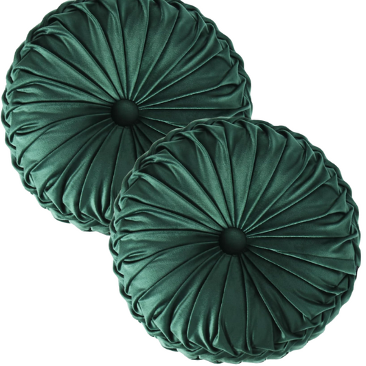 Emerald green velvet round throw pillows with hand-pleated detail and central button, 14.5-inch set of two on a white sofa in a stylish living room.


