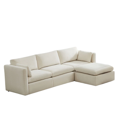 Beige modular four-piece sectional sofa with wide seats, soft chenille fabric, removable cushions, and built-in storage ottoman — ideal for modern and adaptable living room layouts.

