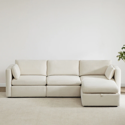 Beige modular four-piece sectional sofa with wide seats, soft chenille fabric, removable cushions, and built-in storage ottoman — ideal for modern and adaptable living room layouts.


