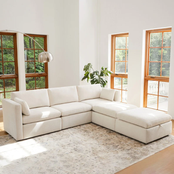 Beige five-piece modular sectional sofa with wide chenille-upholstered seats, two gas-lift storage ottomans, and reversible cushions — a modern and comfortable centerpiece for any living room.

