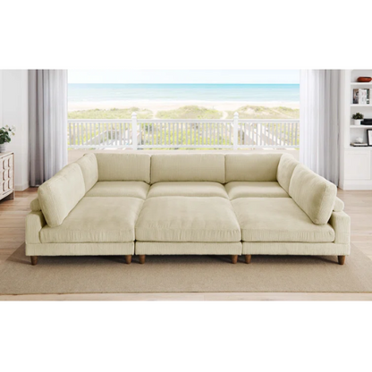 Beige modular sectional sofa with corduroy upholstery, removable cushions, and matching ottoman – seats six in a modern L-shaped or U-shaped layout with solid wood legs.

