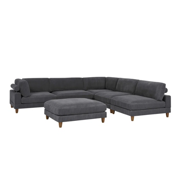 Dark grey modular sectional sofa with soft corduroy upholstery, matching ottoman, and removable cushions — seats six with flexible L- or U-shaped configurations.

