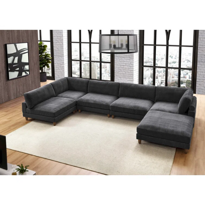 Dark grey modular sectional sofa with soft corduroy upholstery, matching ottoman, and removable cushions — seats six with flexible L- or U-shaped configurations.

