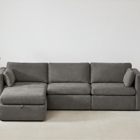 Grey four-piece modular sofa set with wide seats, soft chenille upholstery, removable cushions, and a storage ottoman — ideal for modern, versatile living spaces.

