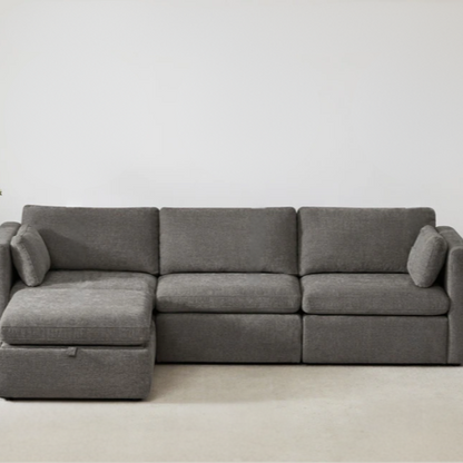 Grey four-piece modular sofa set with wide seats, soft chenille upholstery, removable cushions, and a storage ottoman — ideal for modern, versatile living spaces.

