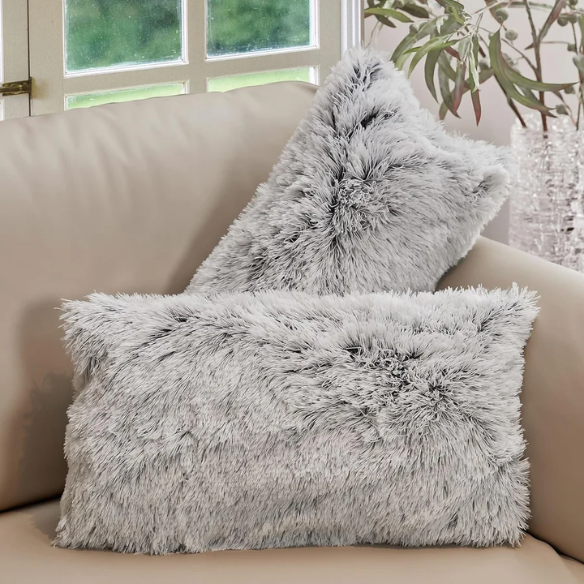 Set of two grey faux fur throw pillows with fluffy texture on a neutral-toned sofa in a modern living room

