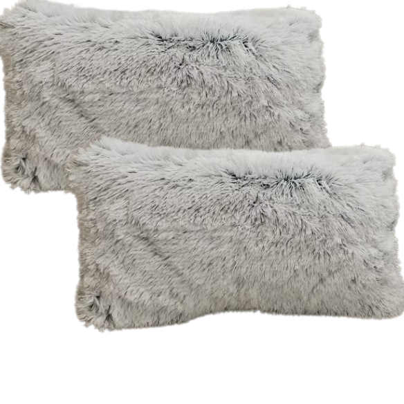 Set of two grey faux fur throw pillows with fluffy texture on a neutral-toned sofa in a modern living room

