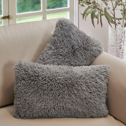 Set of two grey faux fur throw pillows with plush texture on a modern sofa


