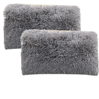Set of two grey faux fur throw pillows with plush texture on a modern sofa

