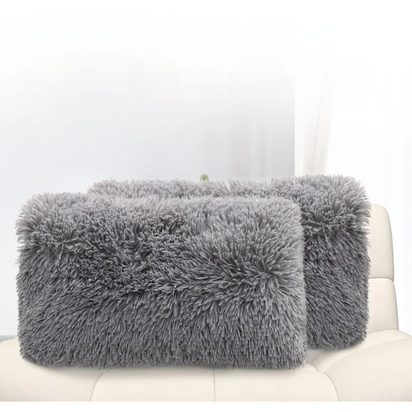 Set of two grey faux fur throw pillows with plush texture on a modern sofa

