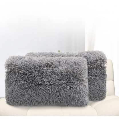 Set of two grey faux fur throw pillows with plush texture on a modern sofa

