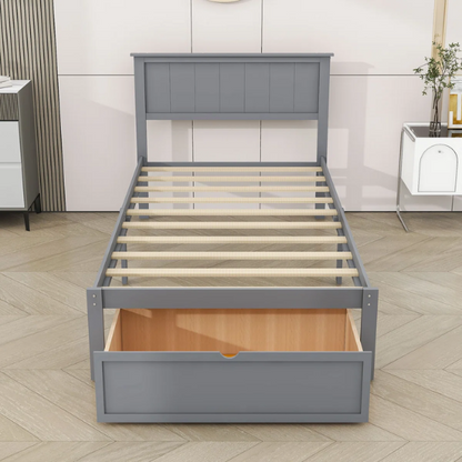Grey twin platform bed made from solid pine wood with a rectangular headboard and a pull-out underbed storage drawer, featuring sturdy center support legs and a clean modern finish.

