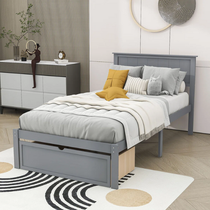 Grey twin platform bed made from solid pine wood with a rectangular headboard and a pull-out underbed storage drawer, featuring sturdy center support legs and a clean modern finish.


