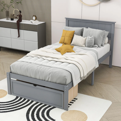 Grey twin platform bed made from solid pine wood with a rectangular headboard and a pull-out underbed storage drawer, featuring sturdy center support legs and a clean modern finish.

