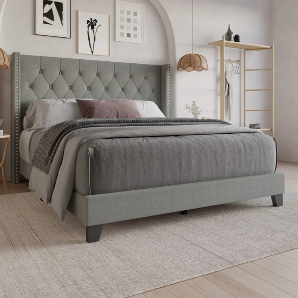 Grey upholstered full-size bed with tufted wingback headboard and nailhead trim