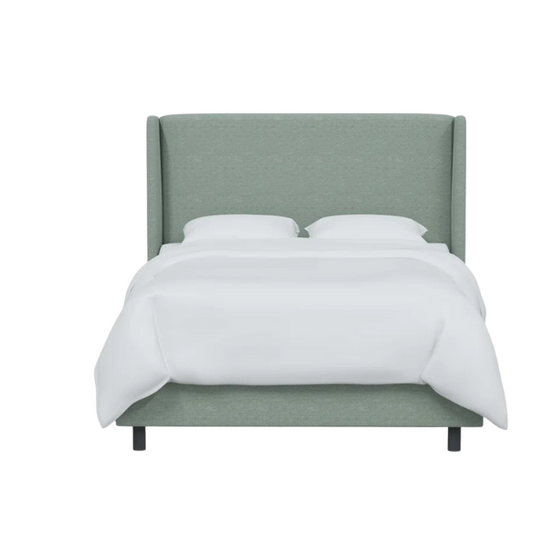 Light green linen upholstered king size bed with foam-padded wingback headboard, black low-profile metal legs, and sturdy wood frame.

