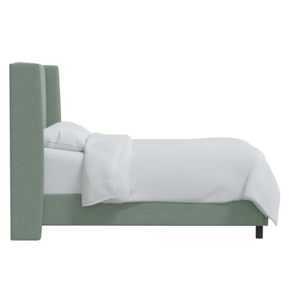 Light green linen upholstered king size bed with foam-padded wingback headboard, black low-profile metal legs, and sturdy wood frame.

