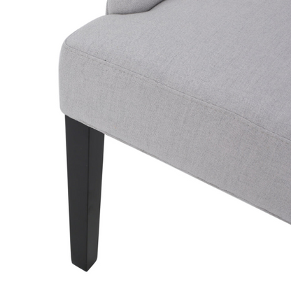 Set of four light grey upholstered dining chairs with diamond tufted backs, armless design, sloped armrests, and espresso brown wood legs.

