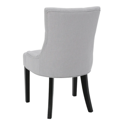 Set of four light grey upholstered dining chairs with diamond tufted backs, armless design, sloped armrests, and espresso brown wood legs.

