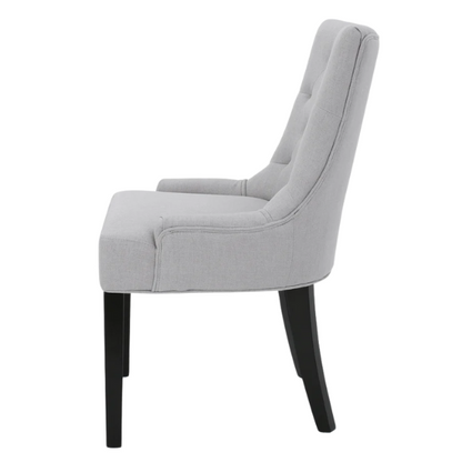 Set of four light grey upholstered dining chairs with diamond tufted backs, armless design, sloped armrests, and espresso brown wood legs.

