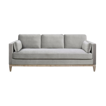 Light grey velvet 3-seater sofa with feather-down cushions, track arms, and natural wood legs, designed for modern and transitional spaces.

