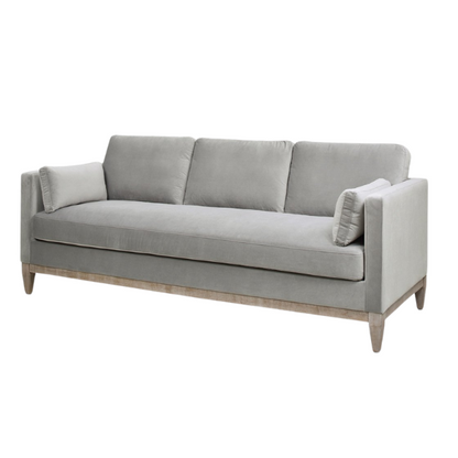 Light grey velvet 3-seater sofa with feather-down cushions, track arms, and natural wood legs, designed for modern and transitional spaces.

