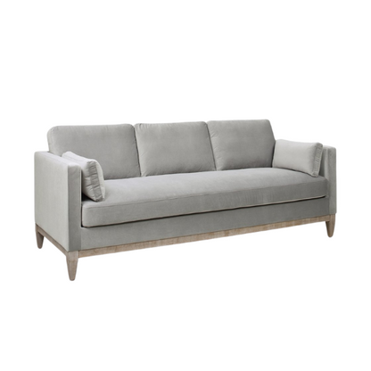Light grey velvet 3-seater sofa with feather-down cushions, track arms, and natural wood legs, designed for modern and transitional spaces.

