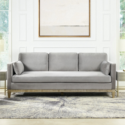 Light grey velvet 3-seater sofa with feather-down cushions, track arms, and natural wood legs, designed for modern and transitional spaces.

