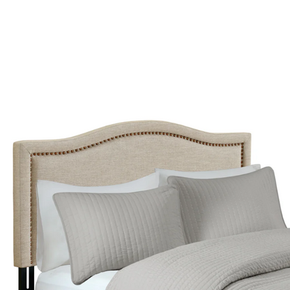 Natural beige upholstered king headboard with curved silhouette, silver nailhead trim, and adjustable metal legs for bed frame mounting

