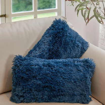 Set of two navy blue faux fur throw pillows with shaggy texture on a neutral-toned modern sofa

