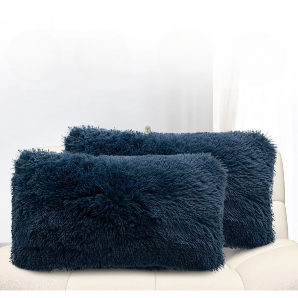 Set of two navy blue faux fur throw pillows with shaggy texture on a neutral-toned modern sofa

