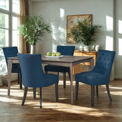 Set of four navy blue upholstered dining chairs featuring diamond tufted backs, armless design, sloped sides, and espresso brown wooden legs.

